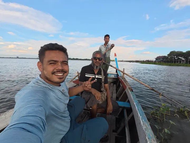 Saif in a small wooden boat on Taungthaman Lake near Mandalay with two local men and a boatman standing at the stern