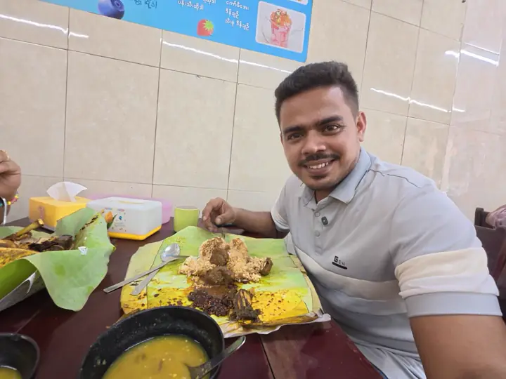 Saif smiling at a restaurant table in Yangon with rice and curry served on banana leaves